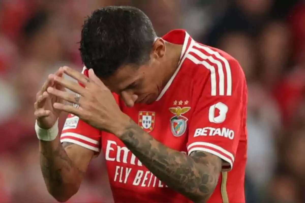 A player in a red Benfica jersey leans forward with hands clasped.