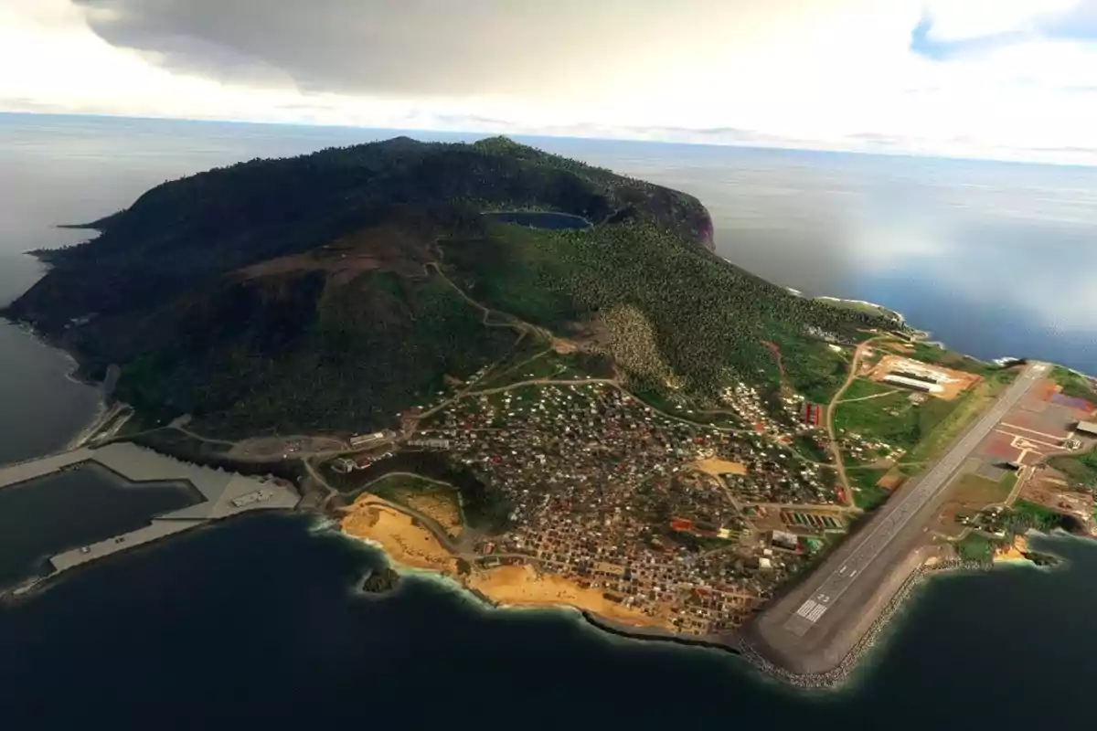 Aerial view of an island with a runway by the sea, an urban area, and hills covered with vegetation