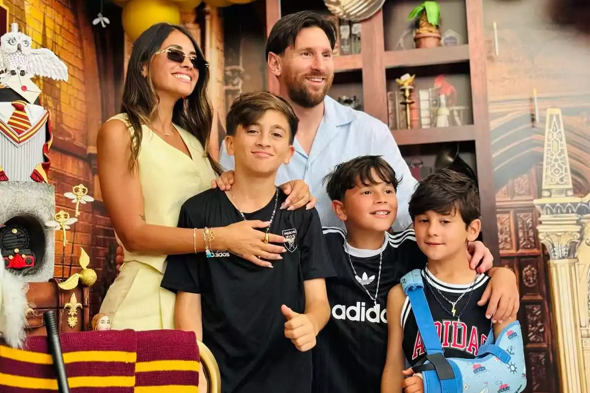 Una familia sonriente posa frente a una decoración temática con un pastel adornado con una figura de búho y detalles de colores rojo y amarillo.