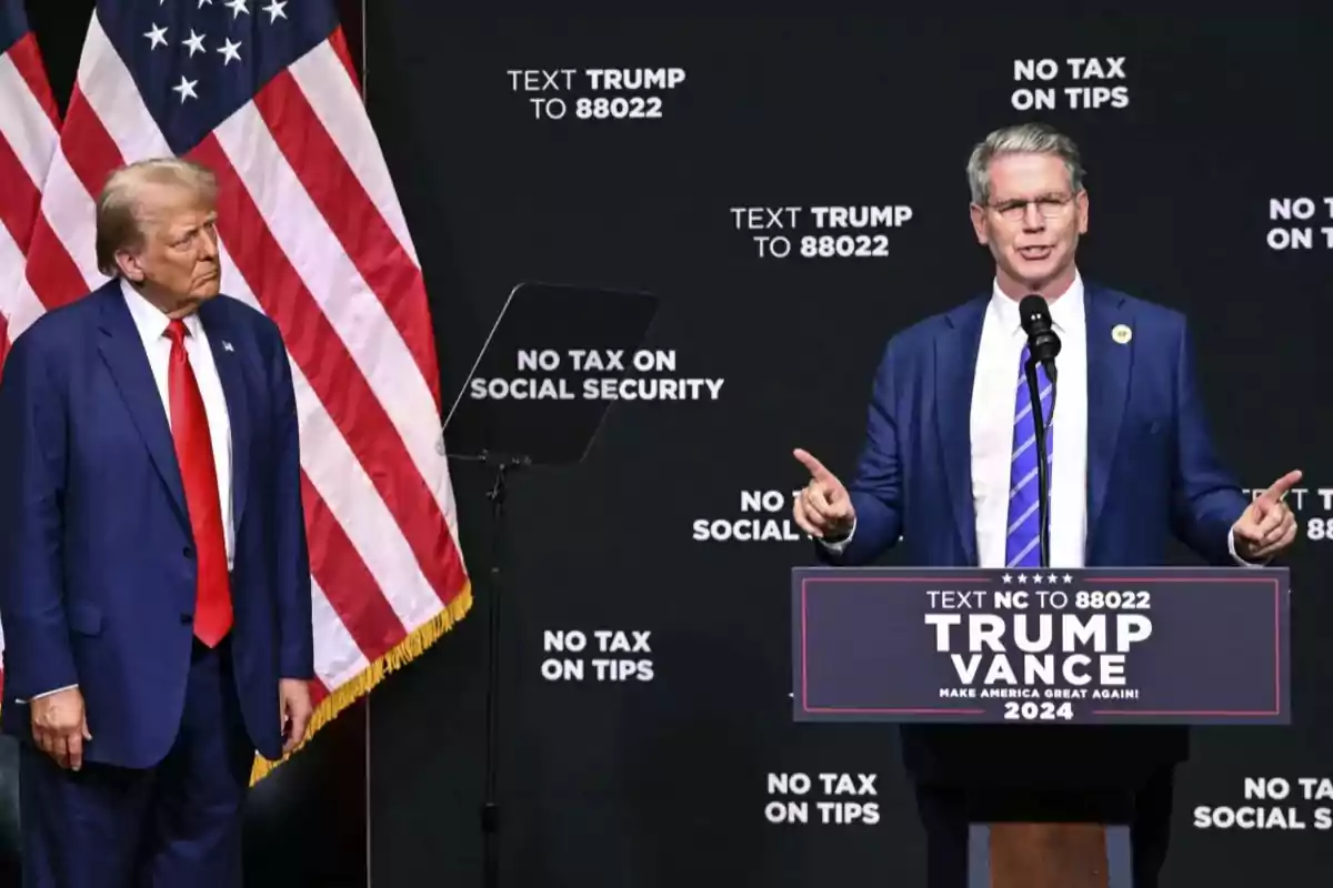 Two men on a stage with American flags in the background, one of them speaking at a podium with messages about taxes and social security.