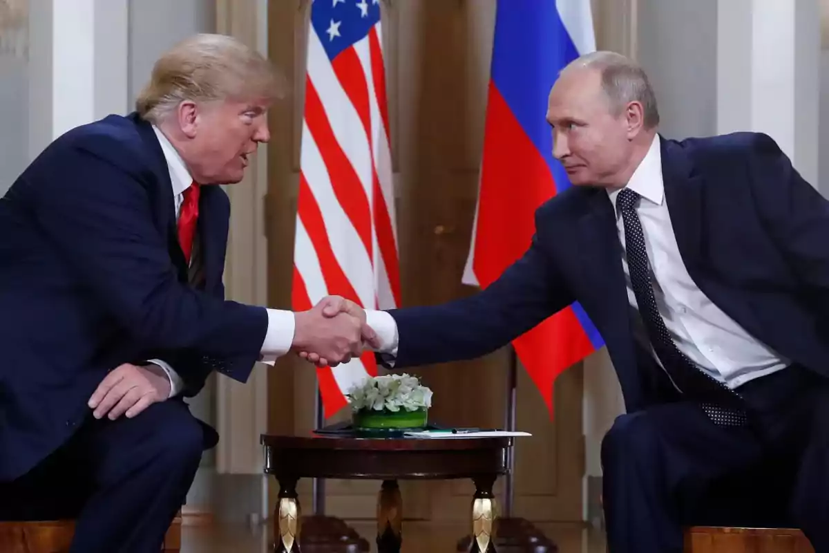 Dos hombres de traje se dan la mano en una reunión formal con banderas de Estados Unidos y Rusia de fondo.