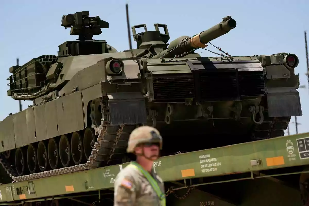 Military tank on a train car with a blurred soldier in the foreground Military tank on a train car with a blurred soldier in the foreground