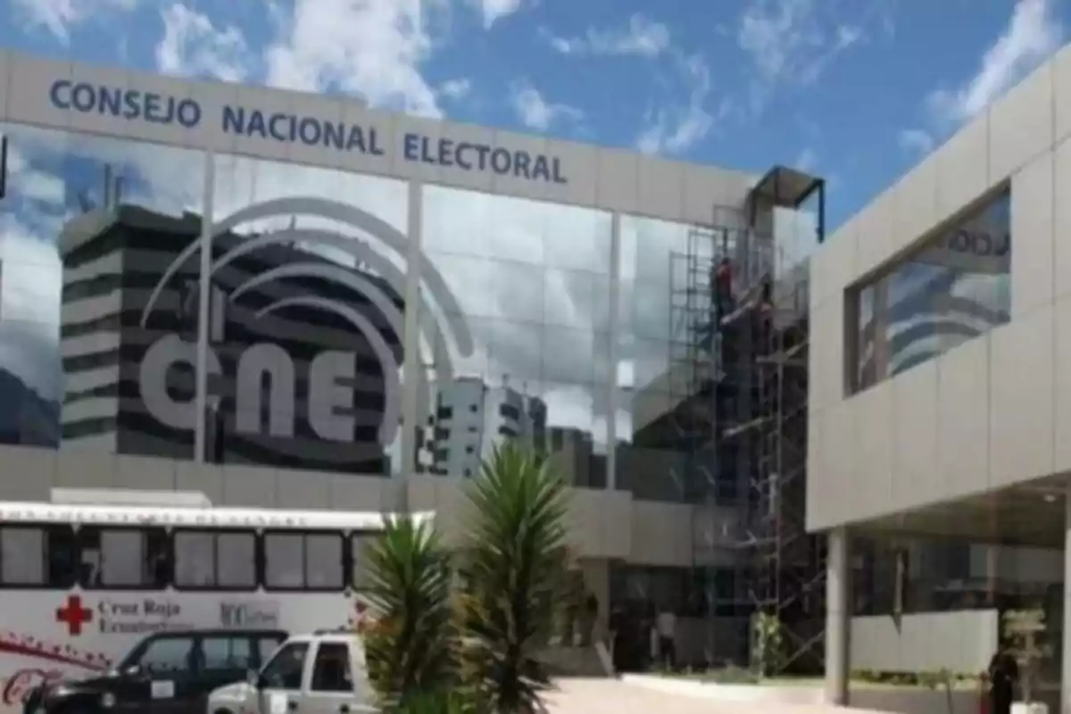 National Electoral Council building with scaffolding and a Red Cross bus parked in front.