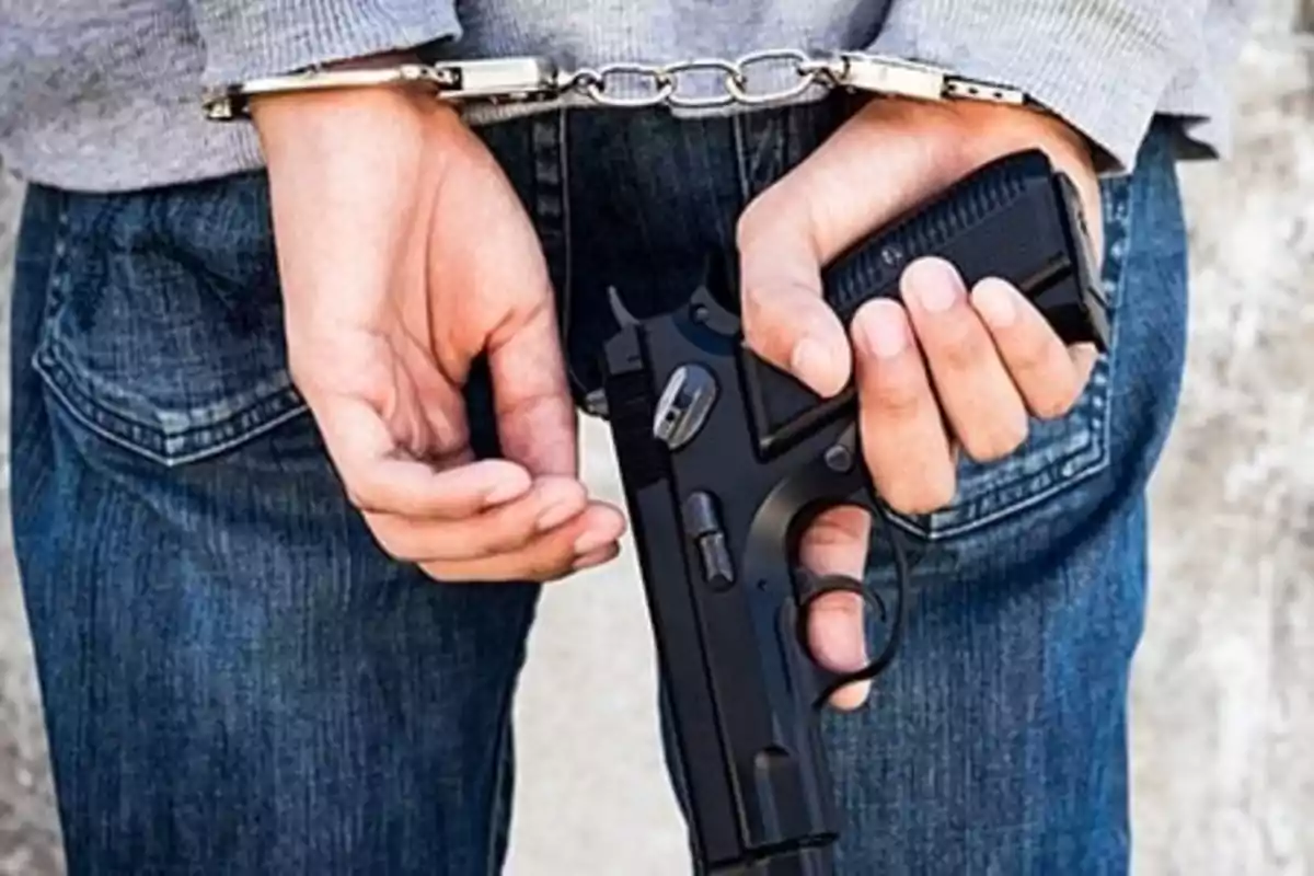 Handcuffed person holding a firearm behind their back. Handcuffed person holding a firearm behind their back.