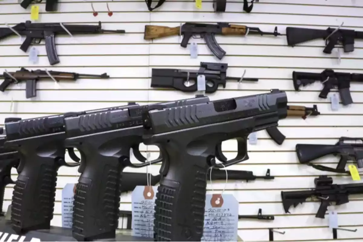 Vitrina de tienda de armas con varias pistolas y rifles exhibidos en estantes blancos