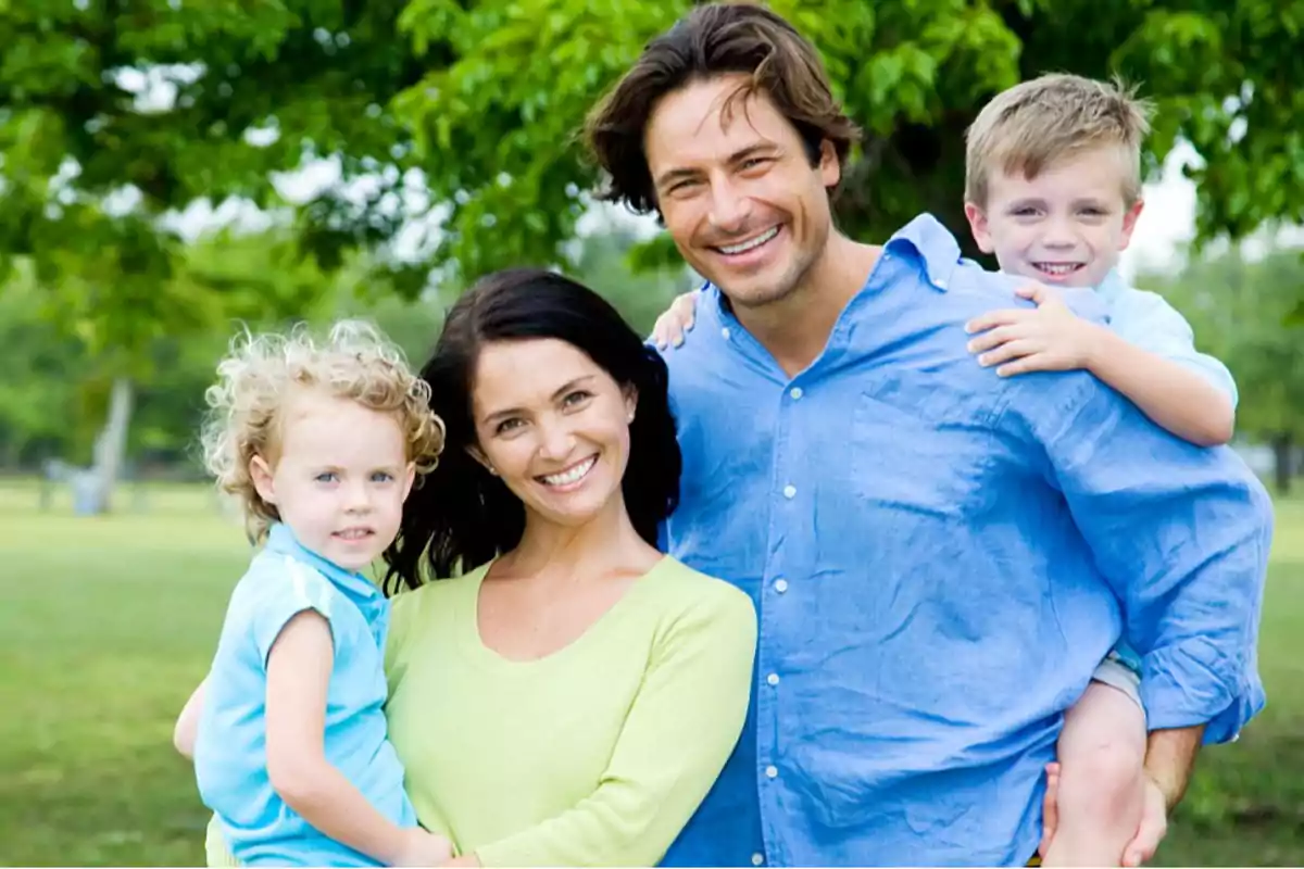 A smiling family posing outdoors in a park. A smiling family posing outdoors in a park.