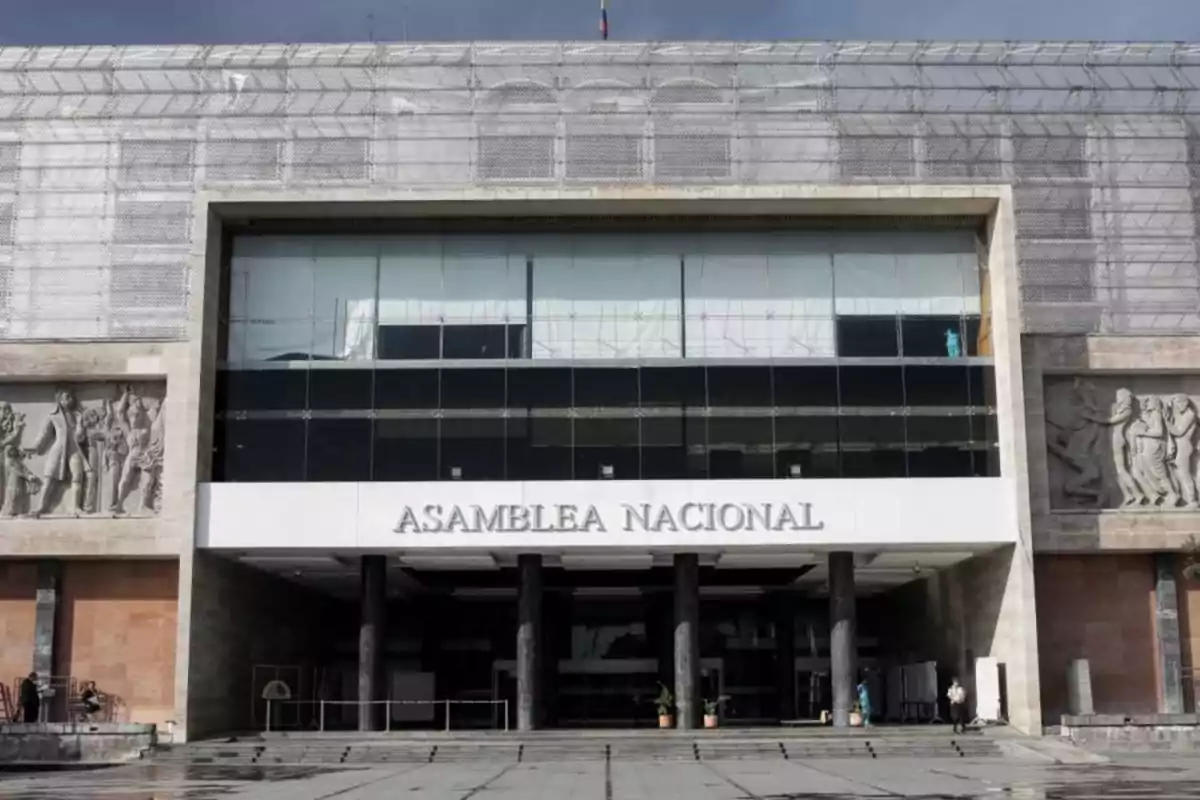 Edificio de la Asamblea Nacional con fachada de vidrio y relieves escultóricos en los laterales.