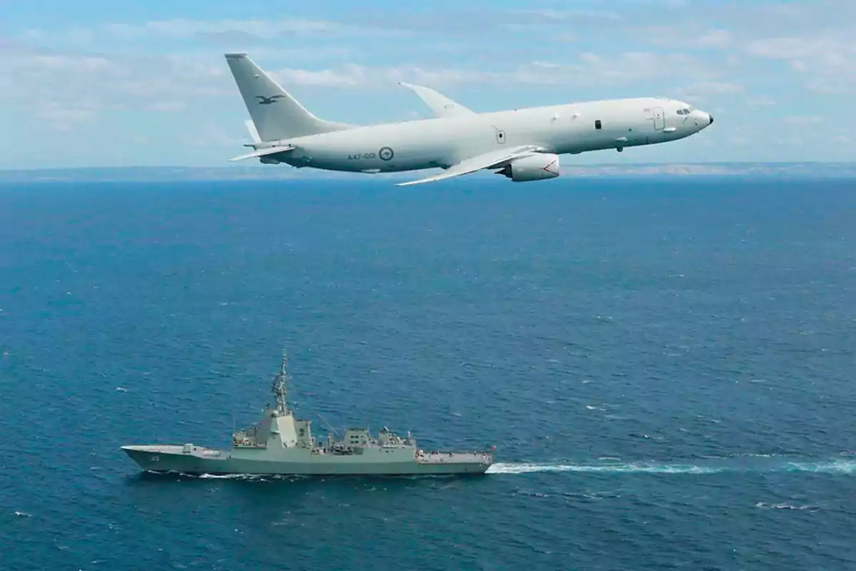 Un avión militar volando sobre un barco en el océano.