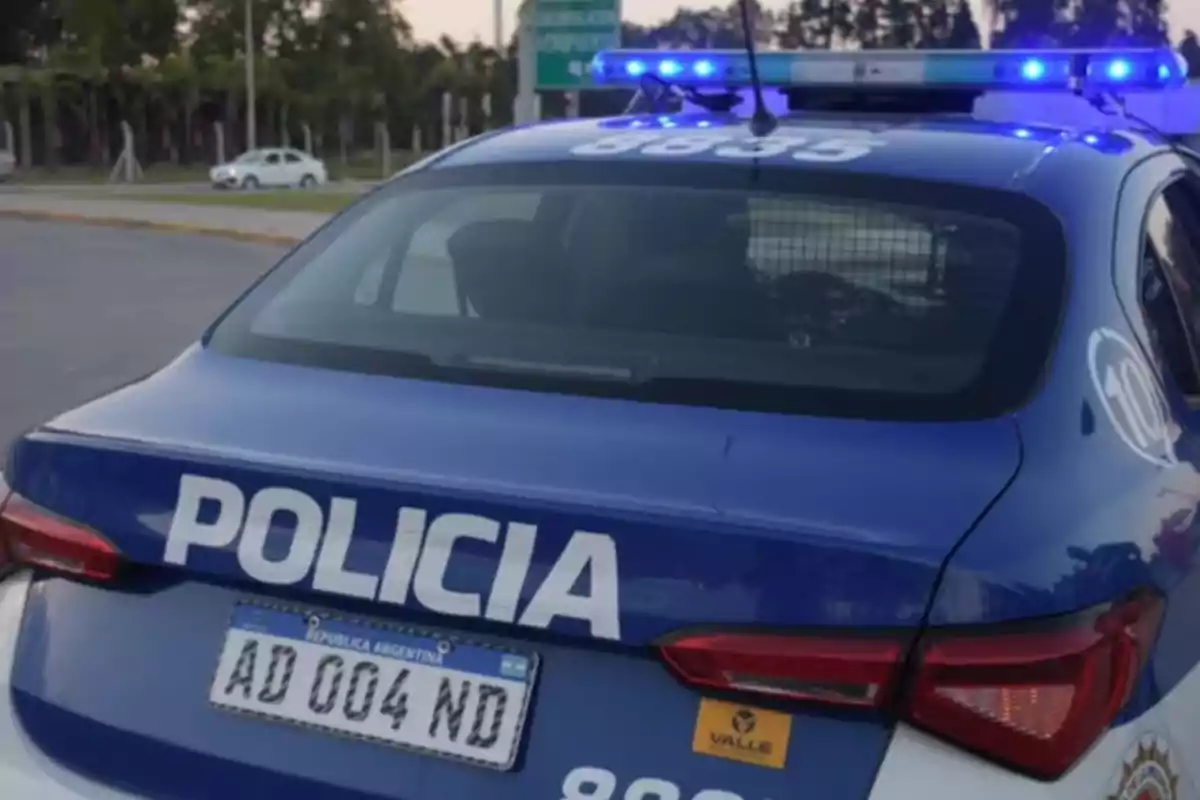 Argentine police patrol car with lights on seen from behind on a public road