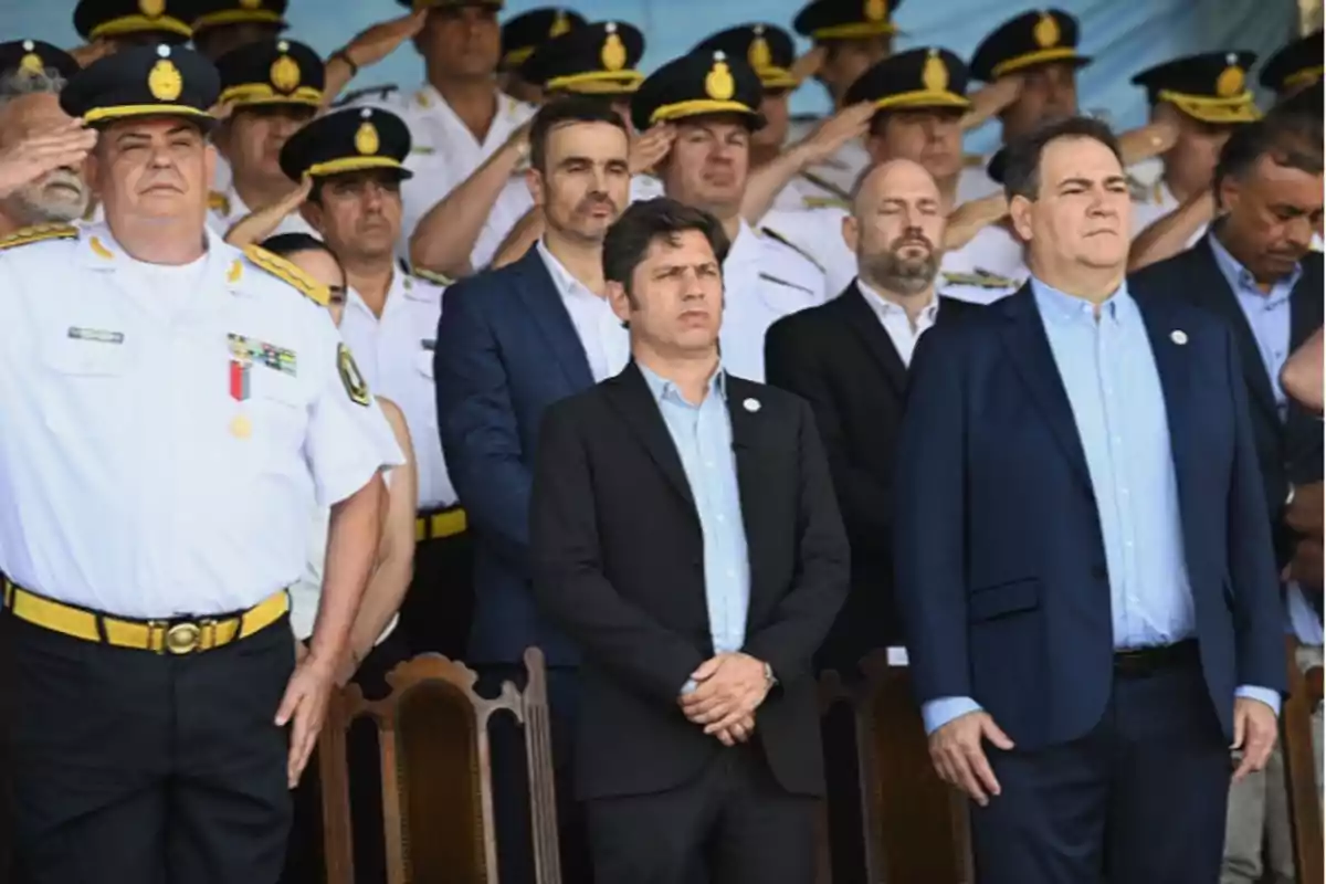 Un grupo de personas, algunas en uniforme, están de pie en una ceremonia oficial.