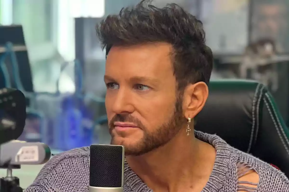 A man with a beard and an earring is in front of a microphone in a studio.