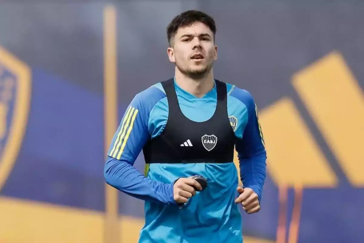 Un jugador de fútbol con uniforme de entrenamiento azul y amarillo corre en un campo deportivo.