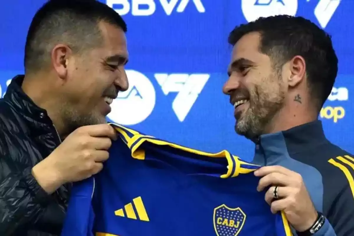 Two people smile while holding a blue and yellow soccer jersey with the CABJ crest on a blue background with logos.