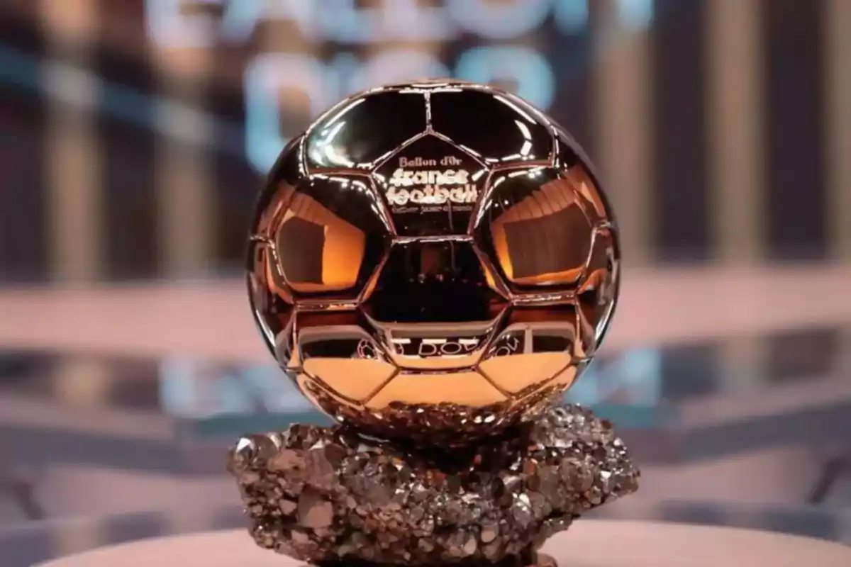 Trofeo dorado del Balón de Oro sobre una base rocosa con fondo desenfocado Trofeo dorado del Balón de Oro sobre una base rocosa con fondo desenfocado