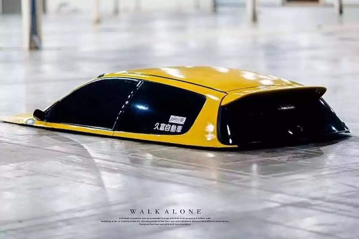 Roof of a modified yellow car that appears to be sunk into the floor of a building Roof of a modified yellow car that appears to be sunk into the floor of a building