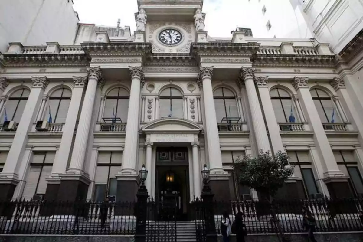 Fachada de un edificio histórico con columnas y un reloj en la parte superior. Fachada de un edificio histórico con columnas y un reloj en la parte superior.