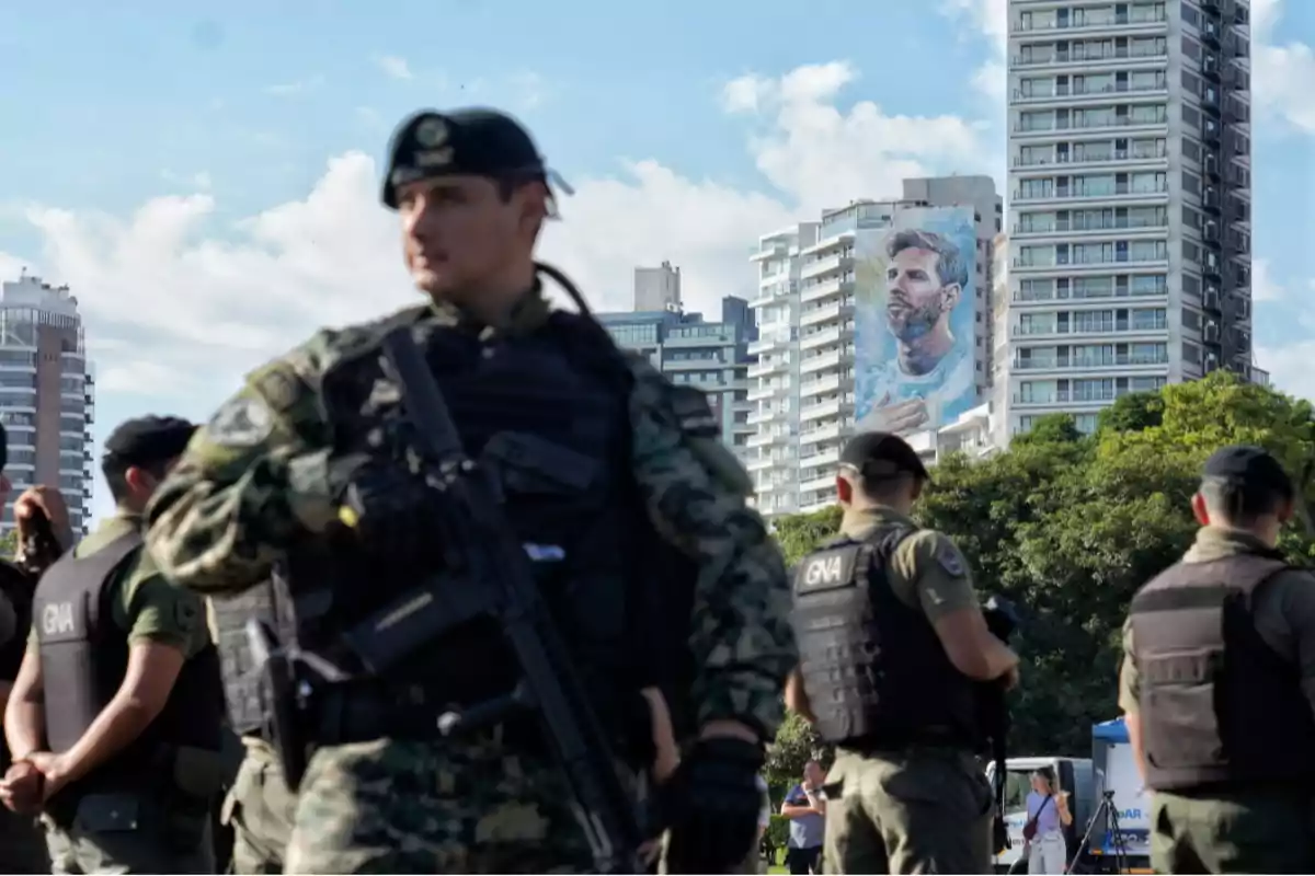 Un grupo de agentes de seguridad con uniformes y chalecos antibalas está de pie en un área urbana con un mural de un futbolista en un edificio al fondo.