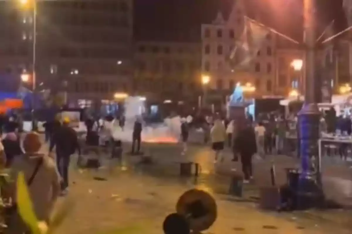 Personas caminando en una plaza de noche con humo y objetos tirados en el suelo, ambiente de disturbio o caos. Personas caminando en una plaza de noche con humo y objetos tirados en el suelo, ambiente de disturbio o caos.