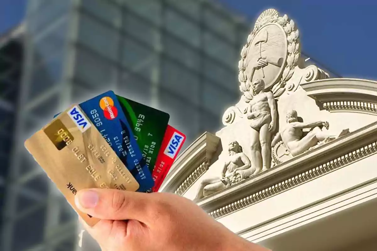 Una mano sosteniendo varias tarjetas de crédito frente a al edificio del Banco Central de la República Argentina