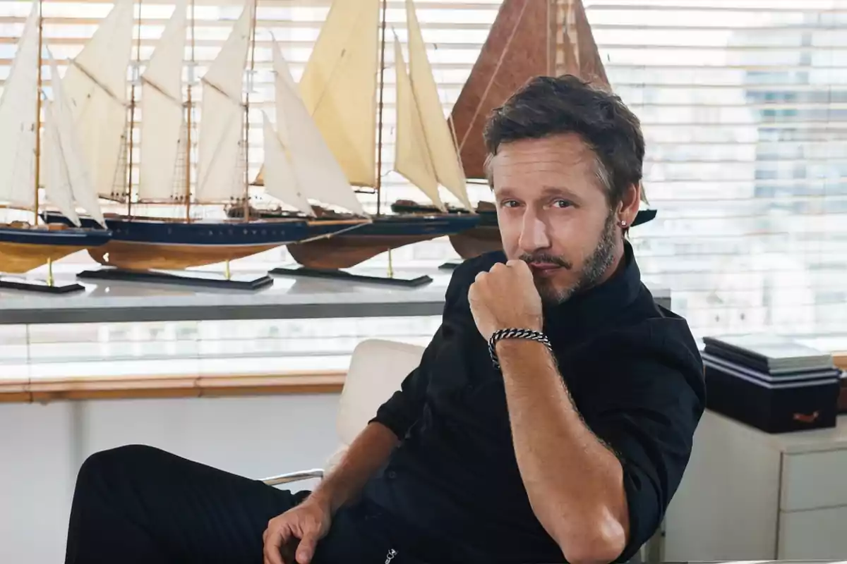 Hombre sentado en una oficina con modelos de barcos de vela en el fondo. Hombre sentado en una oficina con modelos de barcos de vela en el fondo.