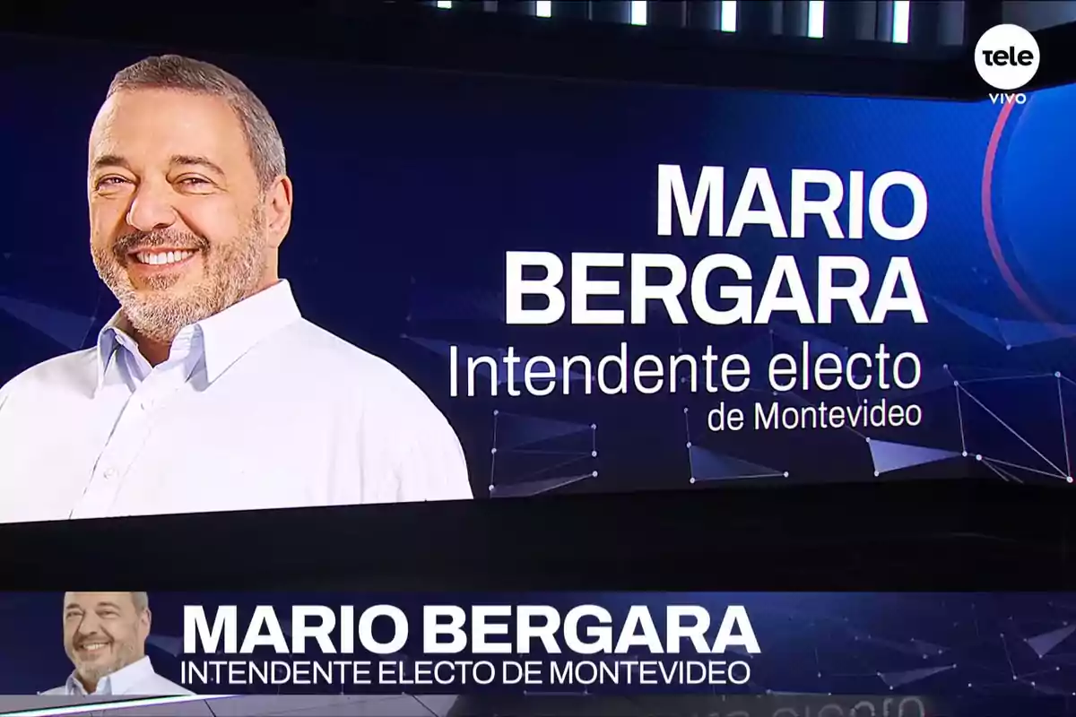 Un hombre sonriente con camisa blanca aparece en un gráfico de televisión que anuncia a un intendente electo de Montevideo.