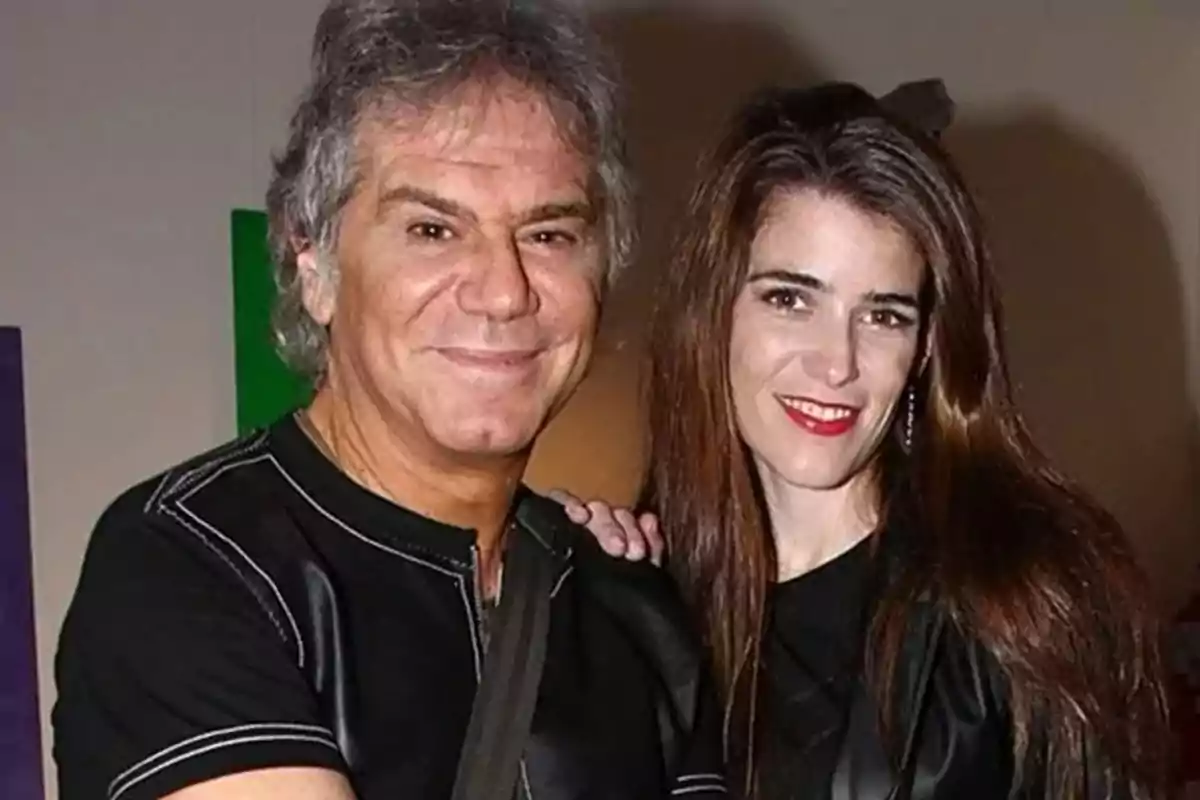 Una pareja sonriente posando para la cámara en un evento social. Una pareja sonriente posando para la cámara en un evento social.