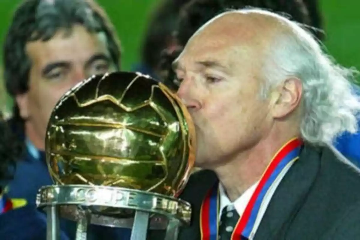 A man kisses a golden trophy while wearing a medal around his neck. A man kisses a golden trophy while wearing a medal around his neck.