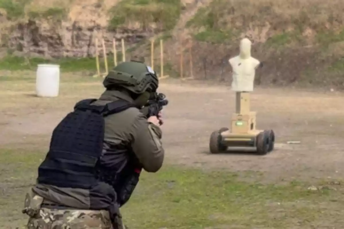 Un soldado en un campo de tiro apunta con su arma a un maniquí de práctica montado sobre una plataforma con ruedas.