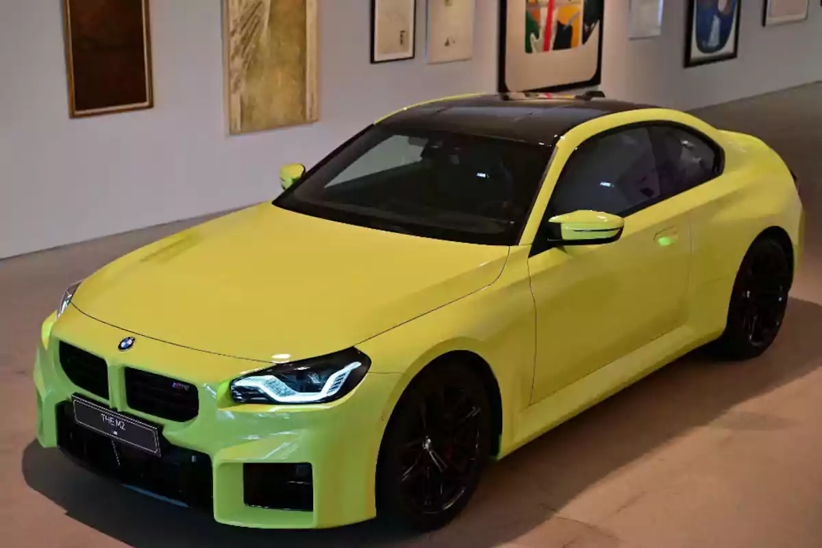 Bright yellow BMW M2 sports car displayed in an art gallery Bright yellow BMW M2 sports car displayed in an art gallery