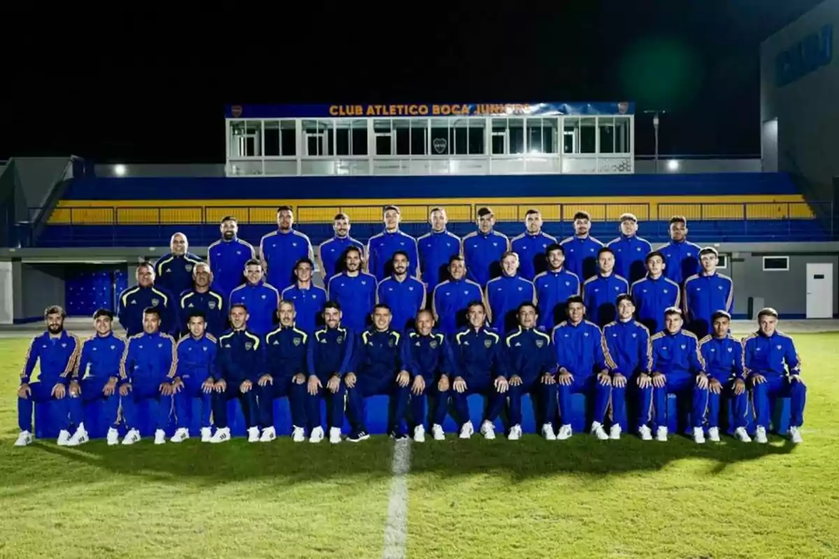 Soccer team posing together in blue uniforms on a field in front of a stand with a sign that reads Club Atlético Boca Juniors