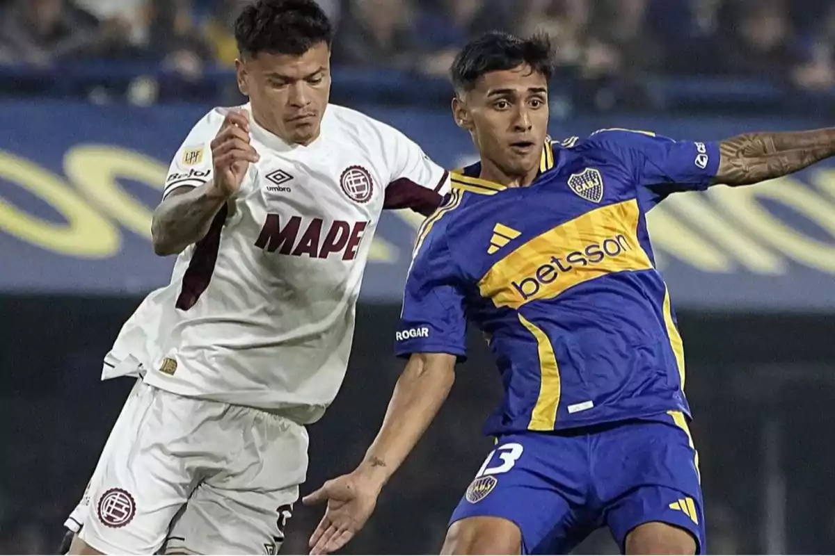 Dos jugadores de fútbol compiten por el balón durante un partido, uno viste uniforme blanco y el otro azul y amarillo. Dos jugadores de fútbol compiten por el balón durante un partido, uno viste uniforme blanco y el otro azul y amarillo.