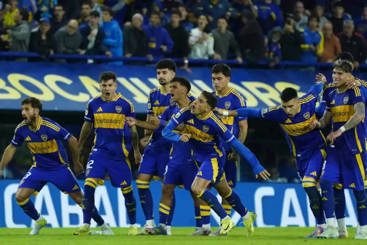 Jugadores de fútbol con uniforme azul y amarillo celebran en el campo mientras el público observa desde las gradas. Jugadores de fútbol con uniforme azul y amarillo celebran en el campo mientras el público observa desde las gradas.