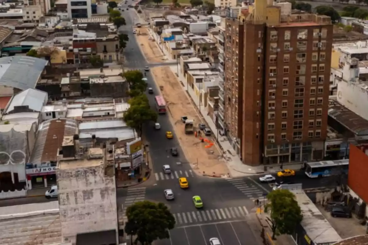 Vista aérea de una avenida en una ciudad con tráfico moderado, edificios altos y una zona en construcción en el centro de la imagen Vista aérea de una avenida en una ciudad con tráfico moderado, edificios altos y una zona en construcción en el centro de la imagen