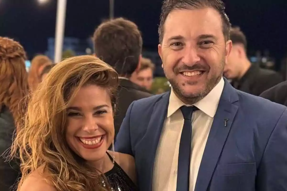 Una mujer y un hombre sonríen mientras posan juntos en un evento nocturno. Una mujer y un hombre sonríen mientras posan juntos en un evento nocturno.