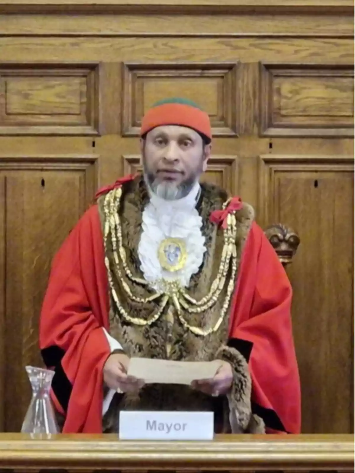 A man dressed in a red and gold ceremonial outfit, with a badge that says A man dressed in a red and gold ceremonial outfit, with a badge that says