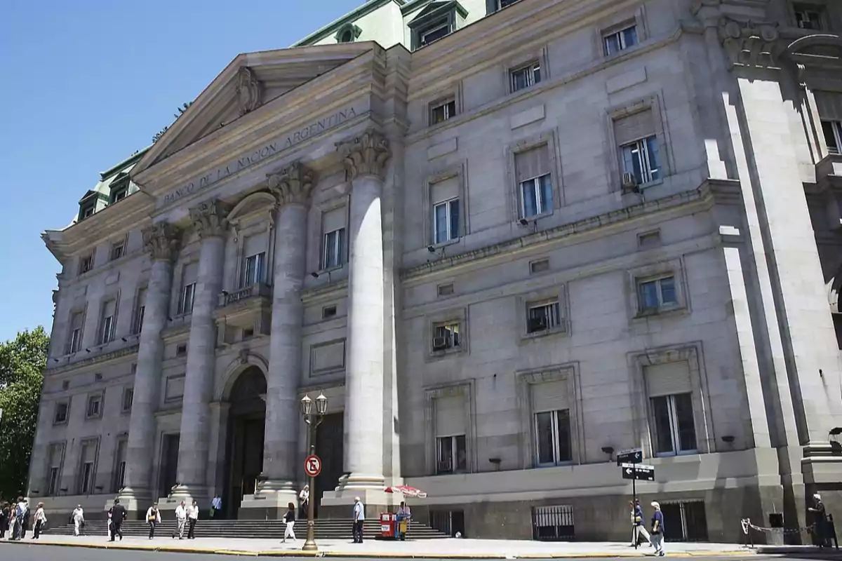 Edificio histórico del Banco de la Nación Argentina con columnas imponentes y personas caminando por la acera.