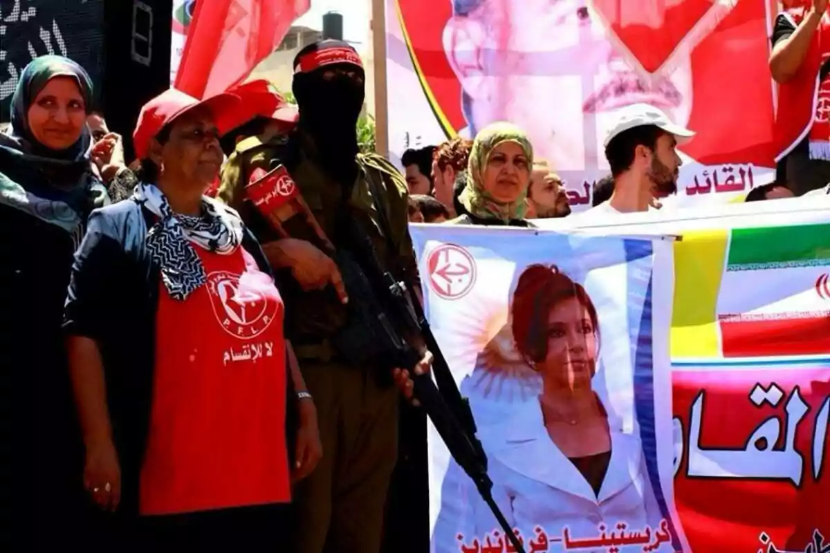 Personas manifestándose con banderas y pancartas, una de ellas con la imagen de una mujer y símbolos del Frente Popular para la Liberación de Palestina Personas manifestándose con banderas y pancartas, una de ellas con la imagen de una mujer y símbolos del Frente Popular para la Liberación de Palestina