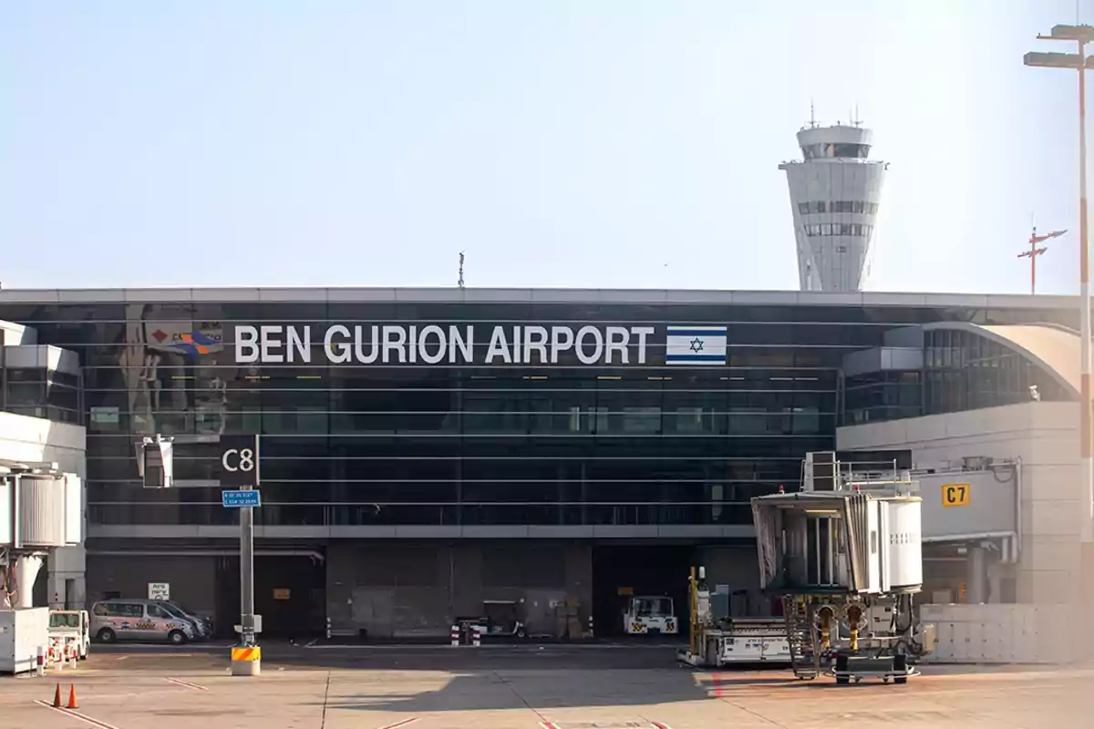 Edificio del aeropuerto Ben Gurion con una torre de control al fondo y una manga de embarque a la derecha. Edificio del aeropuerto Ben Gurion con una torre de control al fondo y una manga de embarque a la derecha.