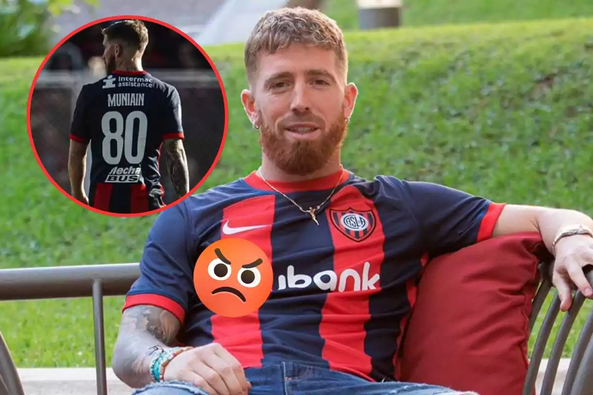 Un hombre con barba y cabello corto está sentado en una silla al aire libre, vistiendo una camiseta de fútbol azul y roja con el logo de un equipo y un emoji enojado sobre su pecho; en un círculo insertado en la imagen, se muestra la parte trasera de la camiseta con el nombre "Muniain" y el número 80.