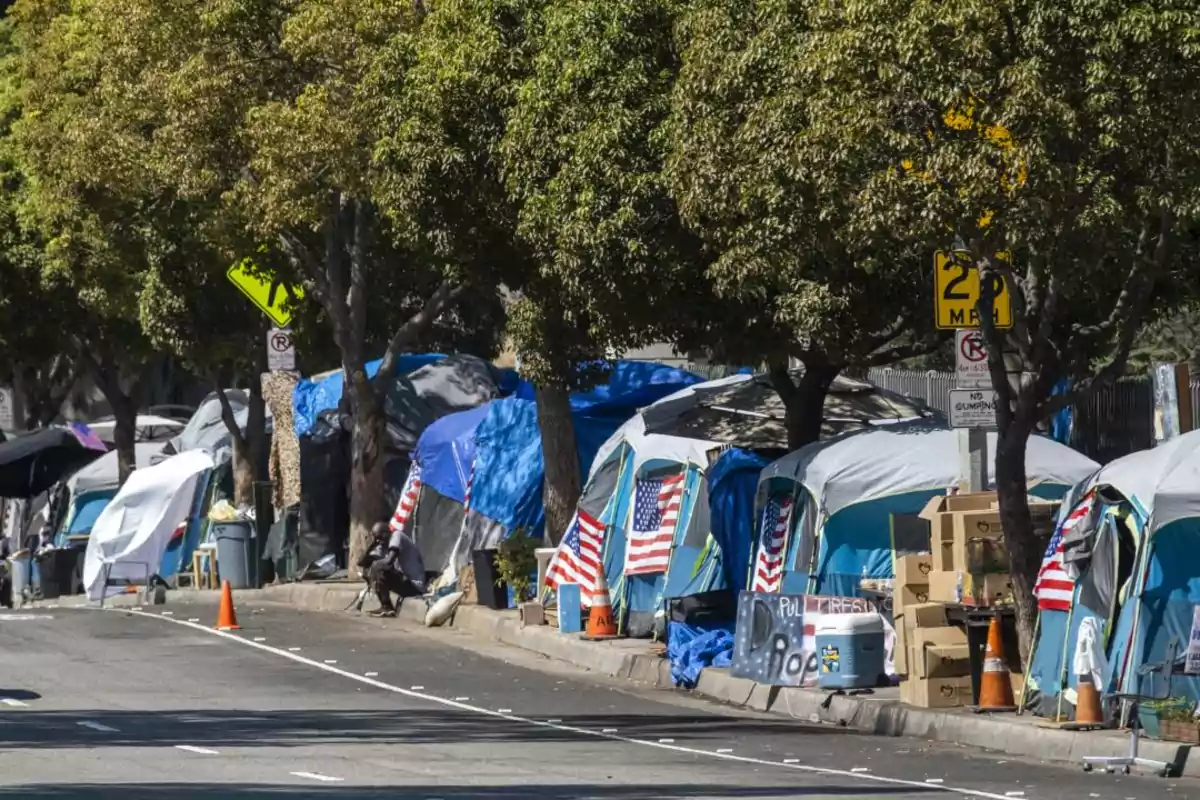 Una fila de tiendas de campaña con banderas estadounidenses en una acera arbolada. Una fila de tiendas de campaña con banderas estadounidenses en una acera arbolada.