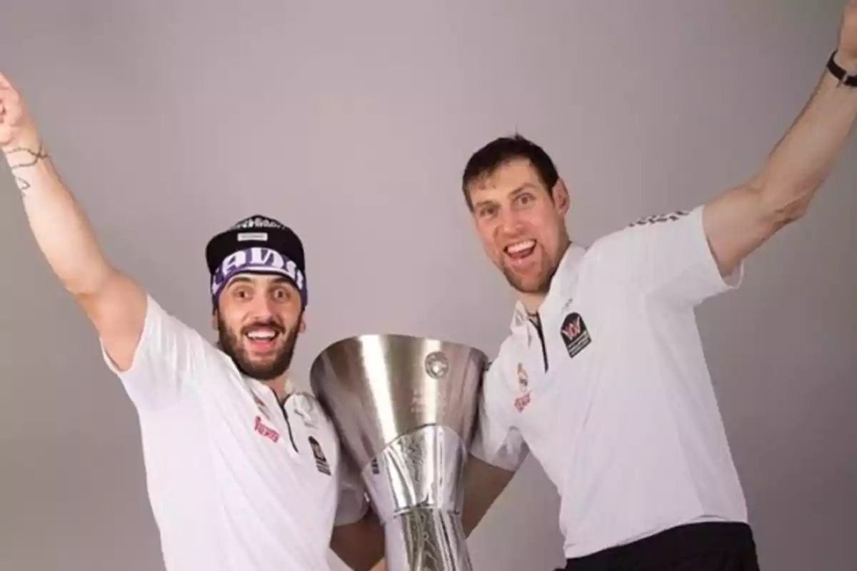 Two people celebrating with a basketball trophy.