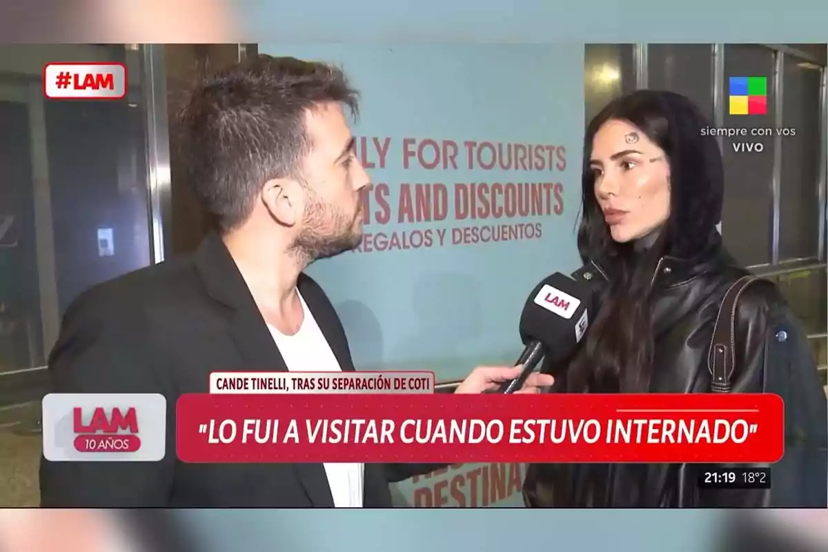 Una entrevista en un programa de televisión donde un reportero sostiene un micrófono con el logo de LAM mientras habla con una mujer que lleva una chaqueta negra y capucha. Una entrevista en un programa de televisión donde un reportero sostiene un micrófono con el logo de LAM mientras habla con una mujer que lleva una chaqueta negra y capucha.