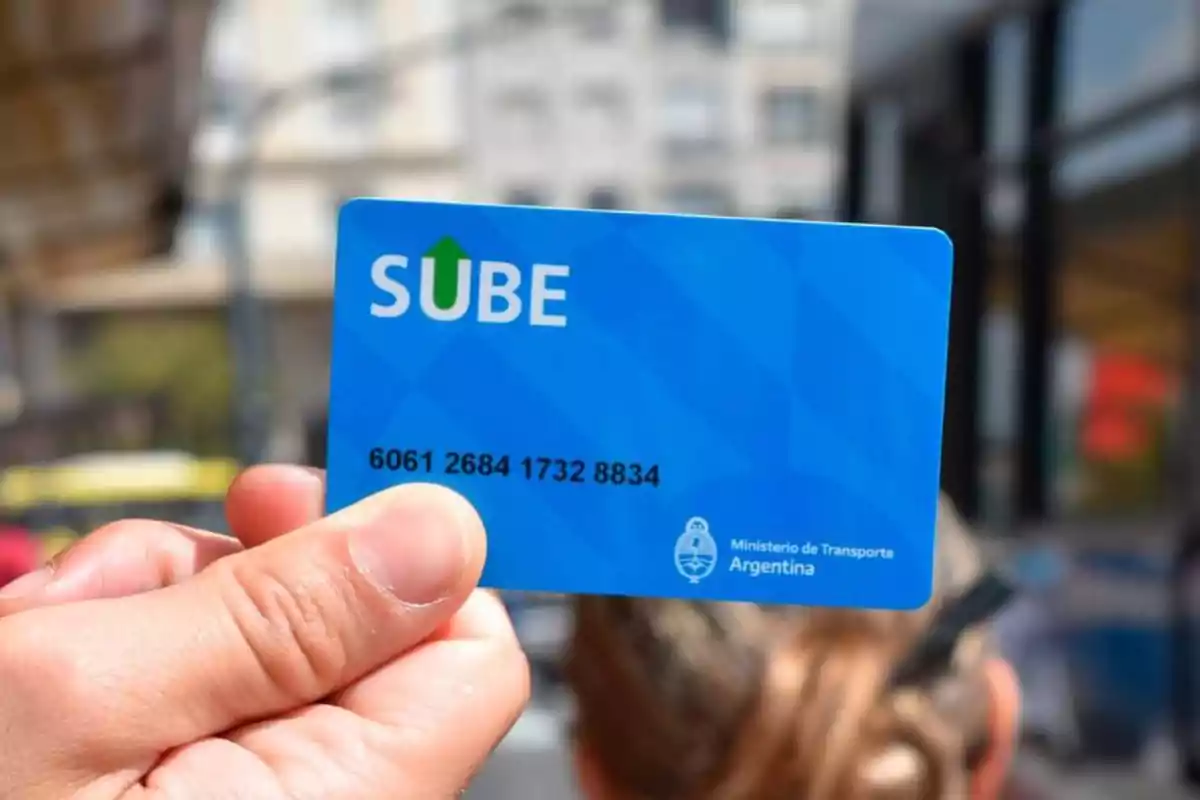 Una mano sosteniendo una tarjeta SUBE del Ministerio de Transporte de Argentina en un entorno urbano.