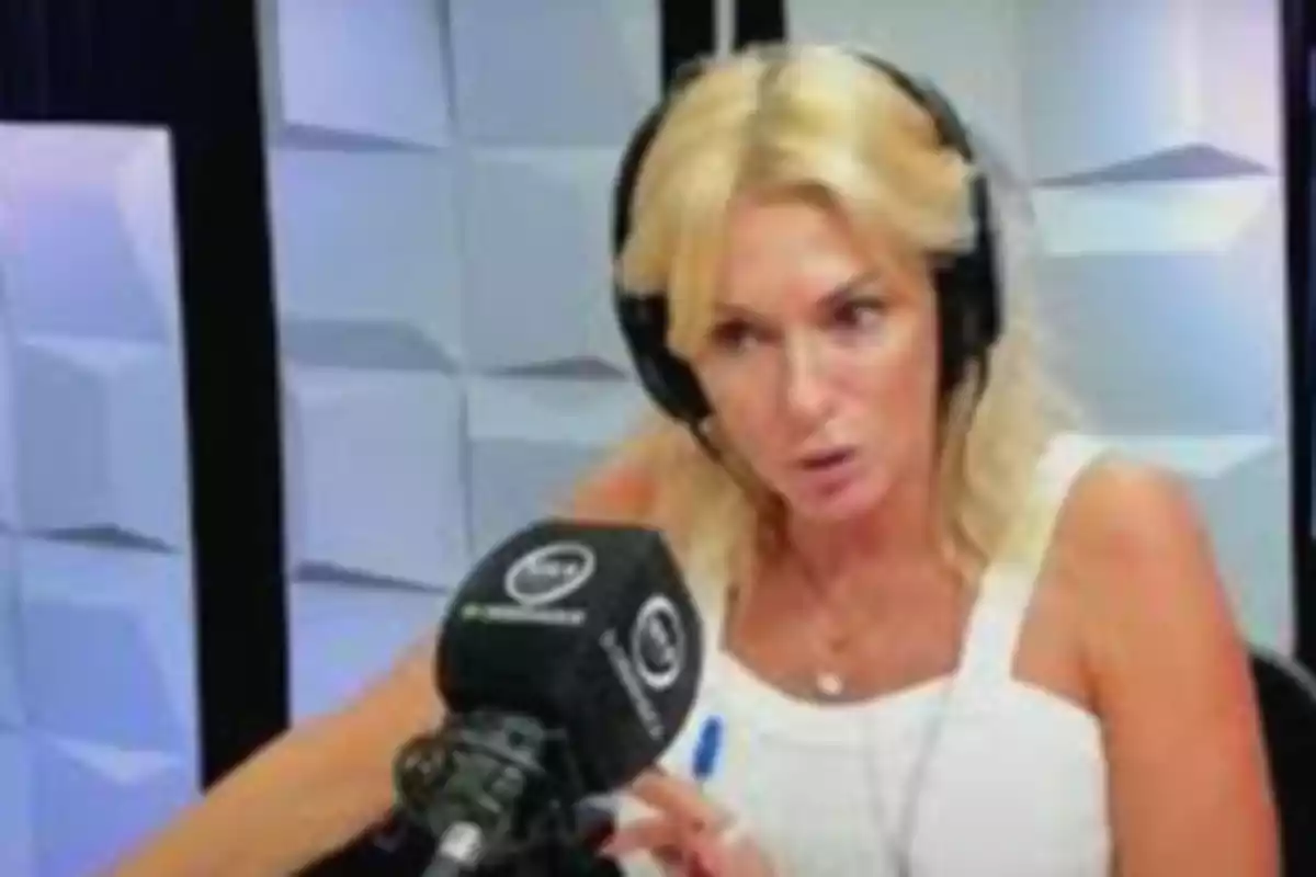 Mujer rubia con auriculares hablando frente a un micrófono en un estudio de radio.