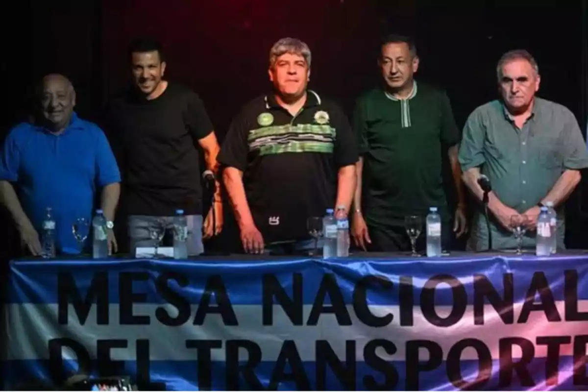 Un grupo de personas de pie detrás de una mesa con un cartel que dice "Mesa Nacional del Transporte".