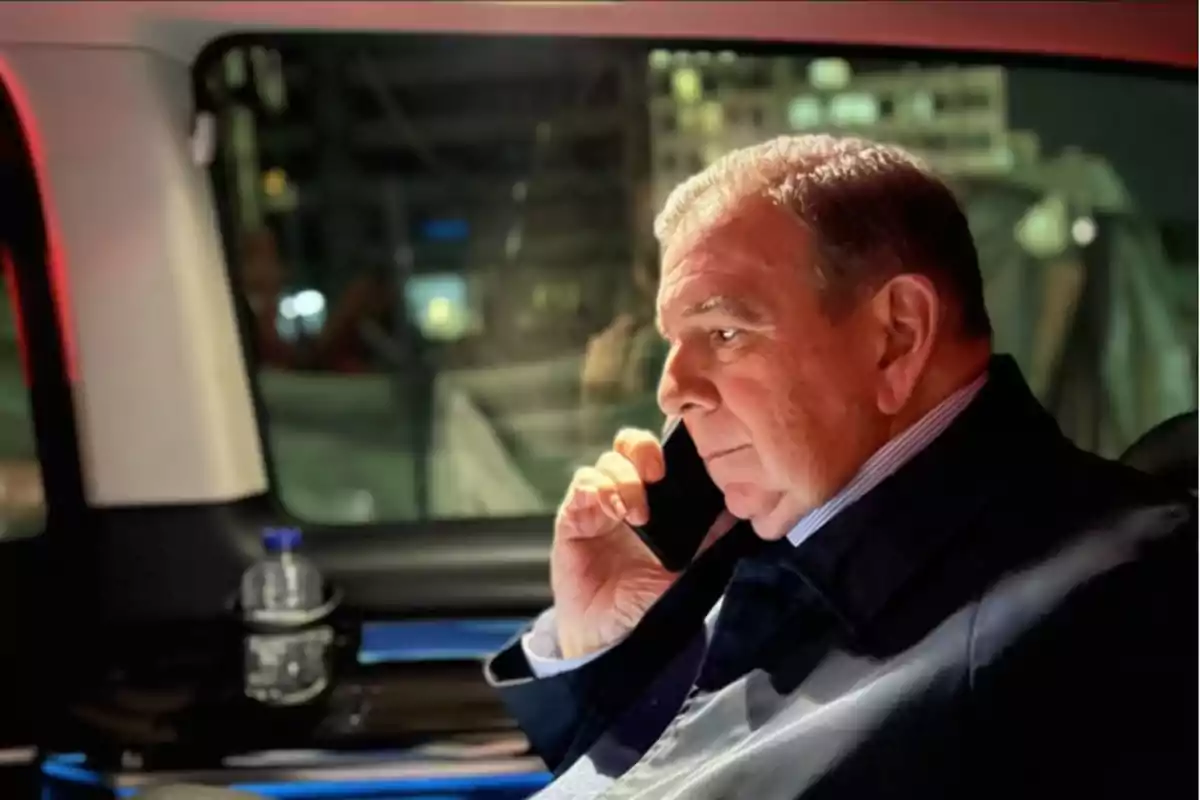 Hombre mayor hablando por teléfono dentro de un automóvil por la noche.