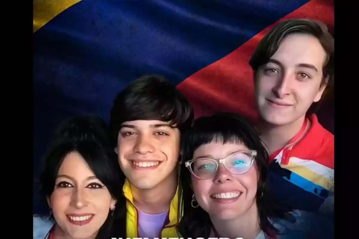 Un grupo de personas sonrientes posando frente a una bandera colorida.