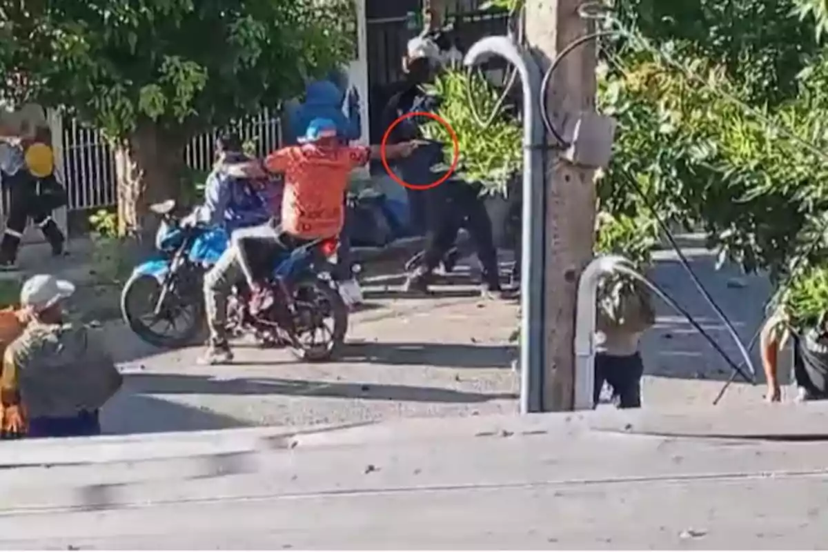 Un grupo de personas en motocicletas y a pie en una calle con árboles y un poste de luz.