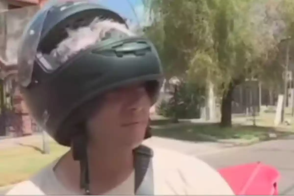 Un hombre lleva un casco de motocicleta al revés mientras está al aire libre en un entorno urbano.