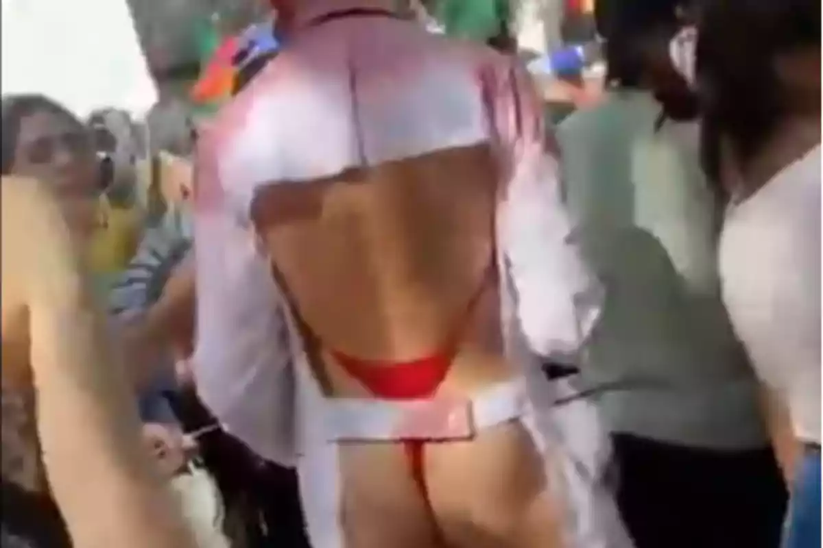 Una persona en un evento al aire libre lleva un disfraz con la espalda descubierta y un traje de baño rojo.